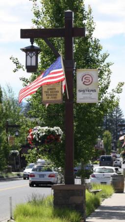 Streetlight with American flag and Chamber of Commerce banner in downtown Sisters